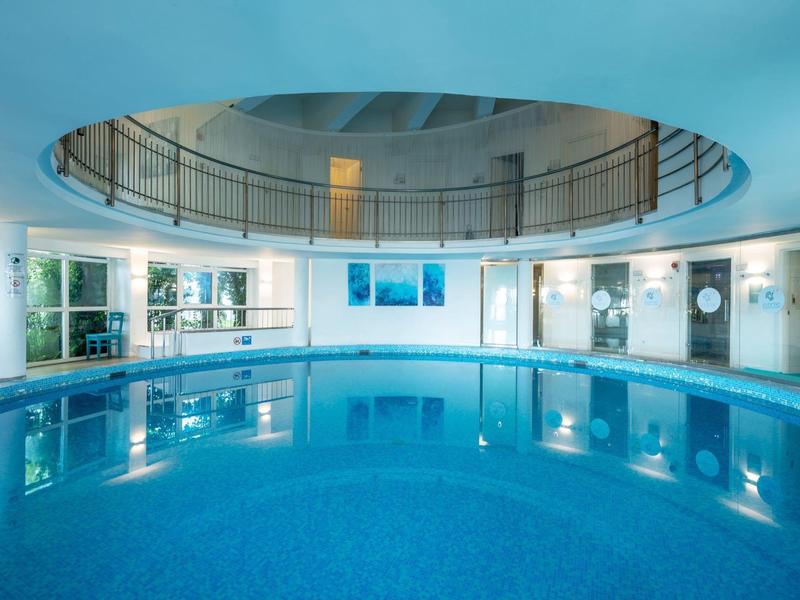 Eleganter Innenpool mit rundem Design und klar blauem Wasser in einem modernen Wellnessbereich.
