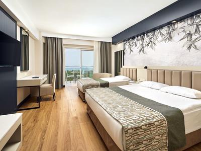 Modernes Hotelzimmer mit Doppelbett, Schreibtisch und Blick auf das Meer aus dem Fenster.