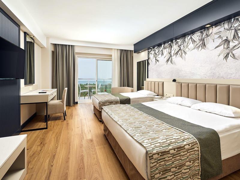 Modern eingerichtetes Hotelzimmer mit Doppelbett, Fernseher, Schreibtisch und großem Fenster mit Ausblick.