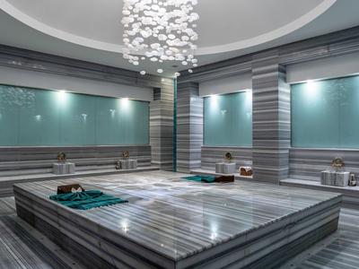 Modern gestaltetes türkisches Hamam mit großer, marmorner Waschplattform und indirekter Beleuchtung.