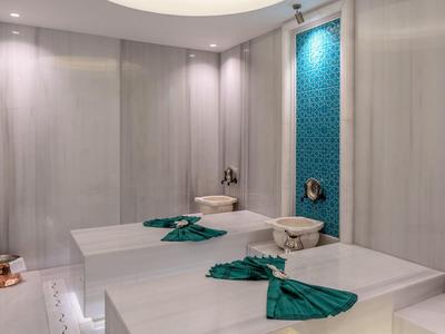 Moderner Hamam mit zwei beheizten Liegen, türkisfarbenen Handtüchern und blau gemusterter Wand.