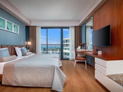 Modernes Hotelzimmer mit Doppelbett, großem Fenster und Blick auf die Stadt und das Wasser.