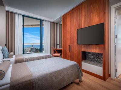 Modernes Hotelzimmer mit Queen-Size-Bett, Sofa und angrenzendem Balkon mit Meerblick.