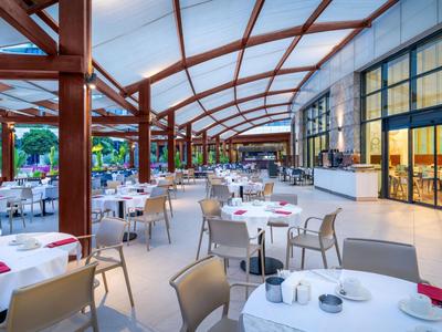 Große überdachte Terrasse eines Restaurants mit Tischen und Stühlen, bereit für Gäste.