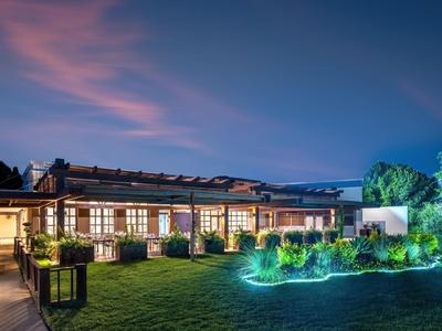 Modernes Gebäude mit beleuchtetem Garten und Pool bei Dämmerung