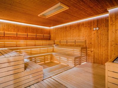 Innenansicht einer modernen Holzsauna mit mehrstufigen Sitzbänken und warmem Licht