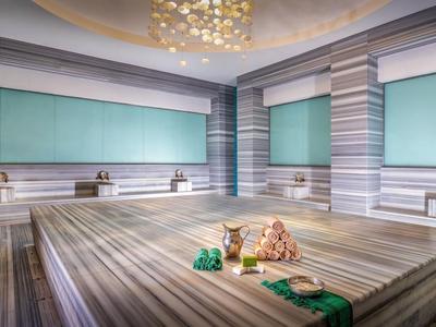 Ein luxuriöser Spa-Raum mit einem großen zentralen Massagebett und sanfter Beleuchtung.