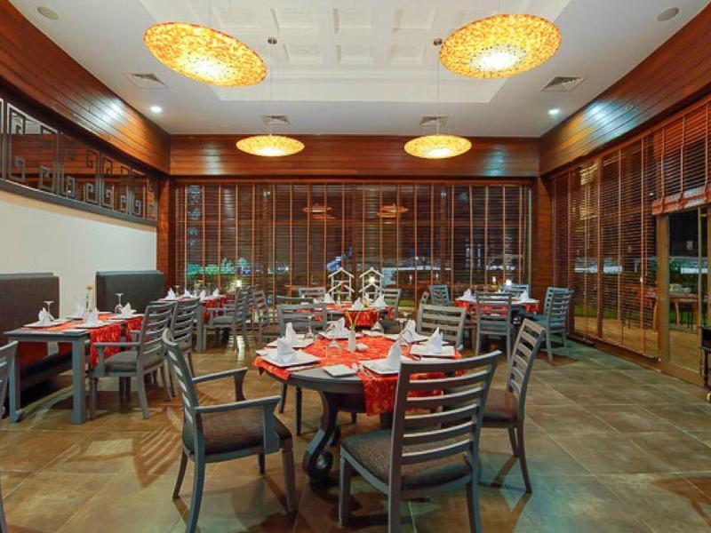 Elegantes Restaurant mit Holzmöbeln, rund gedeckten Tischen und warmem Licht.