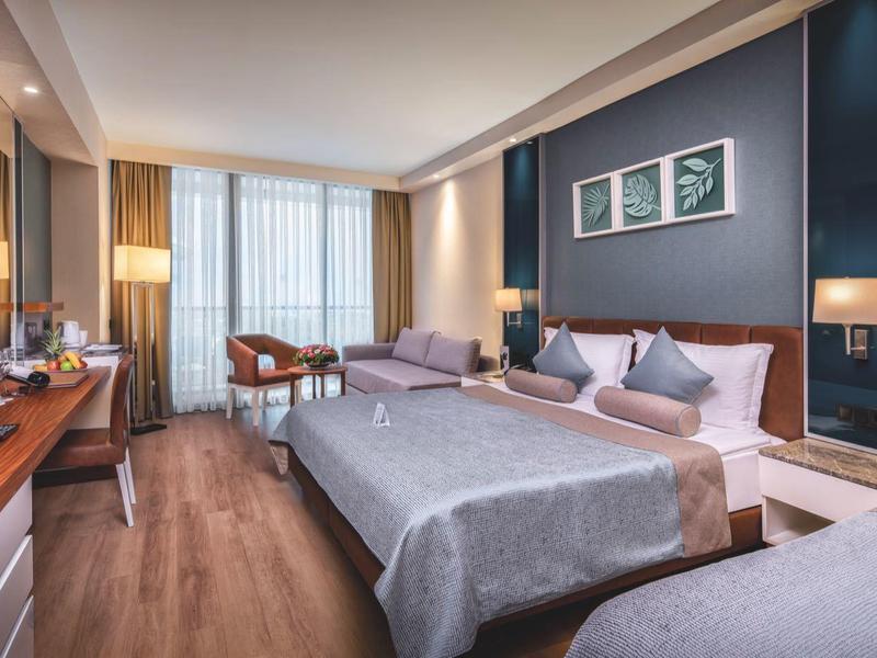 Modernes Hotelzimmer mit zwei Betten, Holzboden, großem Fenster und neutralen Wandfarben.