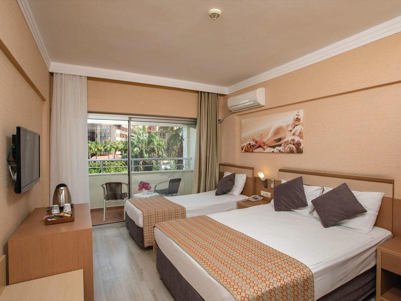 Modernes Hotelzimmer mit Doppel- und Einzelbett, Balkon, Wandbild und neutralen Farben.