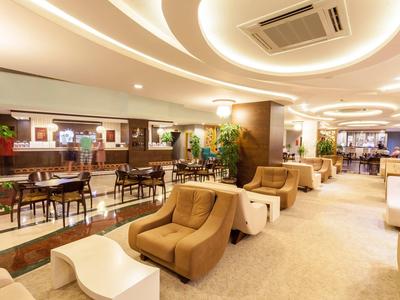 Elegante area lounge dell'hotel con poltrone comode, tavoli e illuminazione decorativa.