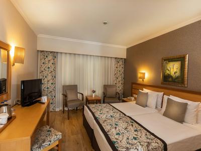 Gemütliches Hotelzimmer mit Doppelbett, Fernseher und Sitzbereich in warmen Farben.