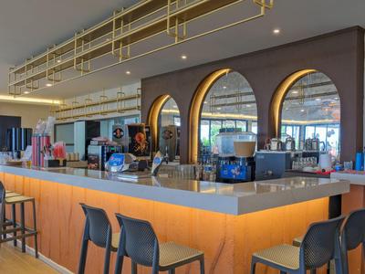 Moderner Hotelbarbereich mit beleuchtetem Tresen und stilvollen Barhockern.