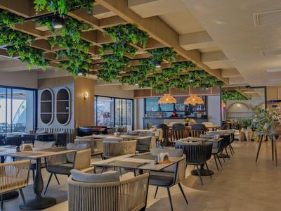 Ristorante moderno con tavoli eleganti e decorazioni verdi al soffitto.