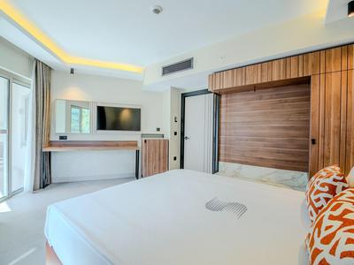 Helles Hotelzimmer mit großem Bett, Holzakzenten und Fernseher an der Wand.