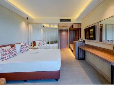 Modernes Hotelzimmer mit großem Bett, Fernseher, Schreibtisch und Spiegel.