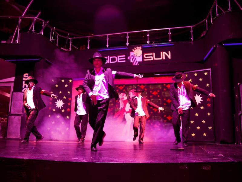 Ballerini eseguono uno spettacolo vivace su un palcoscenico illuminato di rosa.