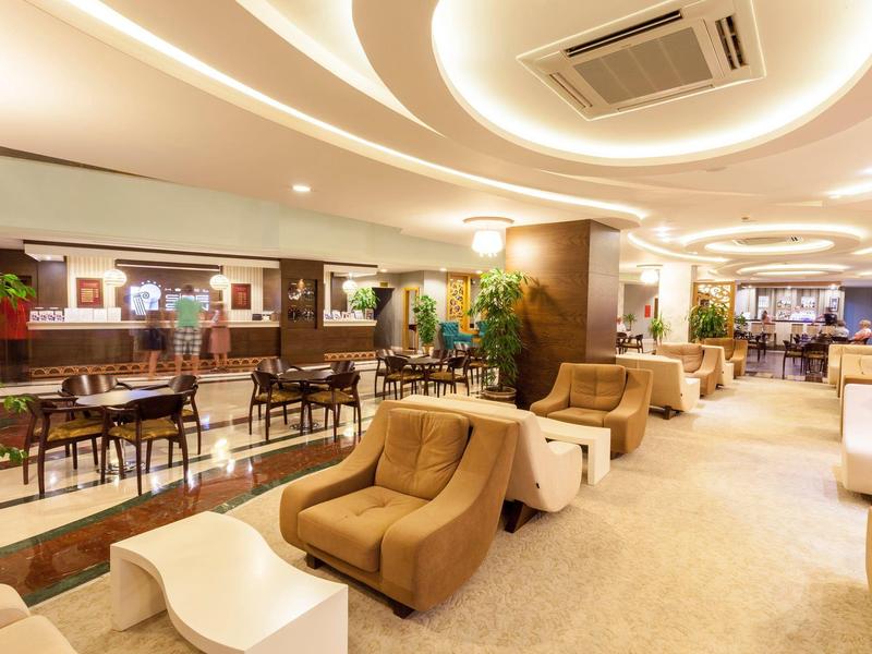 Elegante area lounge dell'hotel con poltrone comode, tavoli e illuminazione decorativa.