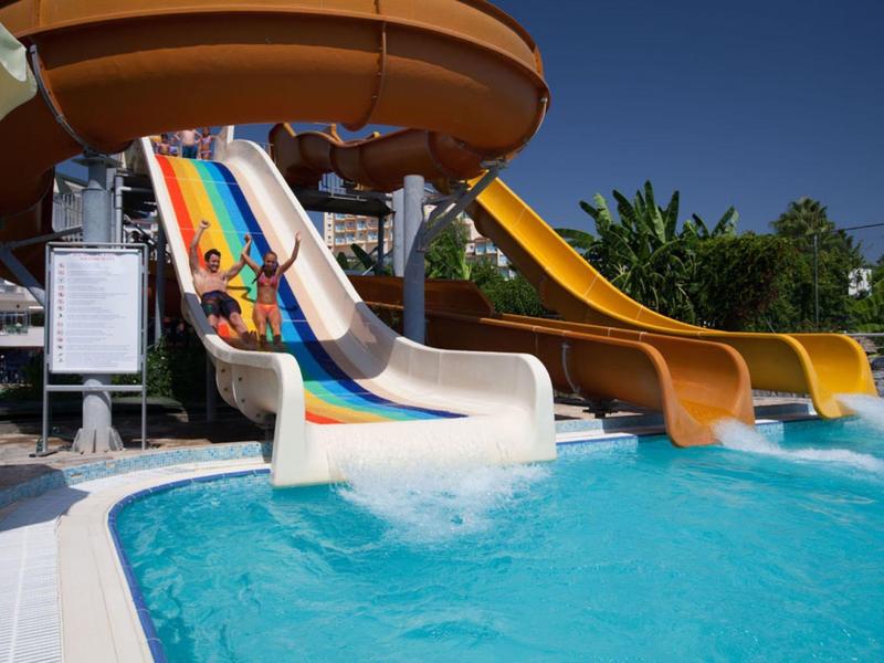 Bambini che scivolano da scivoli d'acqua colorati in una piscina.