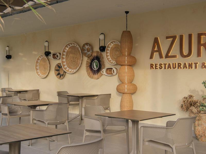 Ristorante moderno con tavoli in legno, sedie, decorazioni da parete e insegna Azure.