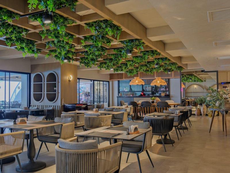 Ristorante moderno con tavoli eleganti e decorazioni verdi al soffitto.