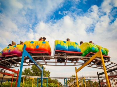 Bunte Achterbahn mit Menschen bei klarem Himmel in einem Freizeitpark.