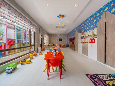 Hell eingerichteter Kinderspielraum mit großen Fenstern und buntem Mobiliar in einem Hotel.