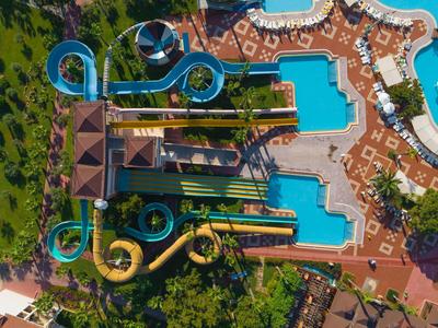 Luftaufnahme eines Wasserparks mit mehreren Wasserrutschen und Pools neben grünen Bäumen.