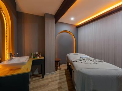 Modern eingerichteter Massageraum mit grauem Massagetisch und warmem Licht.