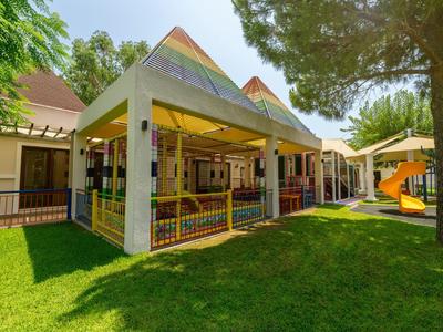 Kinderspielplatz mit überdachtem Bereich und Rutsche im Garten eines Hotels.