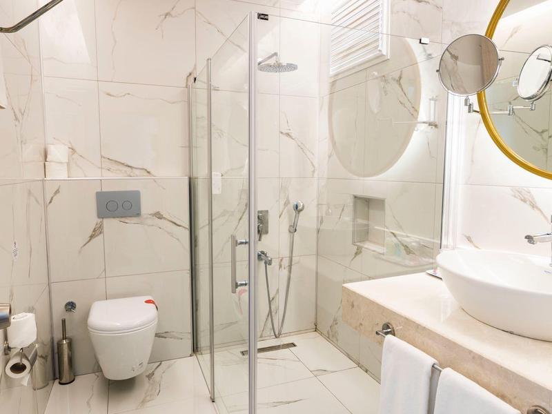 Bagno moderno e luminoso con cabina doccia a tutta altezza, lavabo e WC.