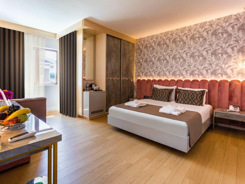 Camera d'hotel moderna con letto grande, carta da parati elegante e pavimento in legno.