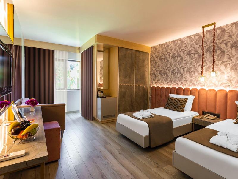 Camera d'hotel moderna con due letti, finestra grande e colori caldi e accoglienti.