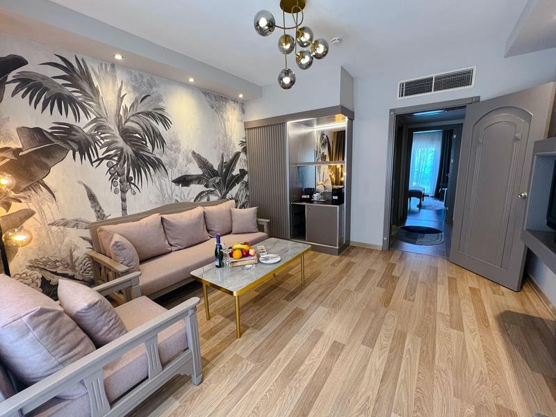 Soggiorno moderno con murale di palme e divano beige.