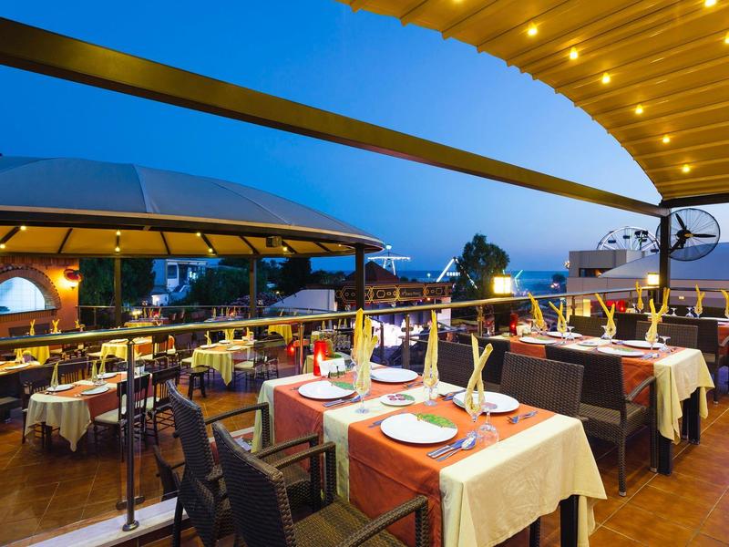 Ristorante sul tetto serale con tavoli apparecchiati e illuminazione d'atmosfera.