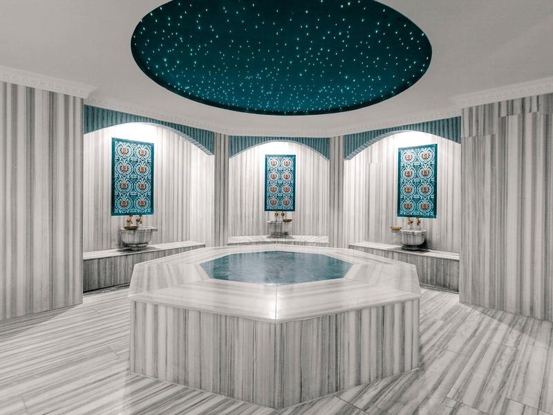 Area benessere moderna con vasca idromassaggio esagonale e illuminazione a soffitto a cielo stellato