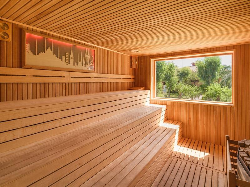 Sauna con interno in legno e grande finestra con vista sulla natura verde