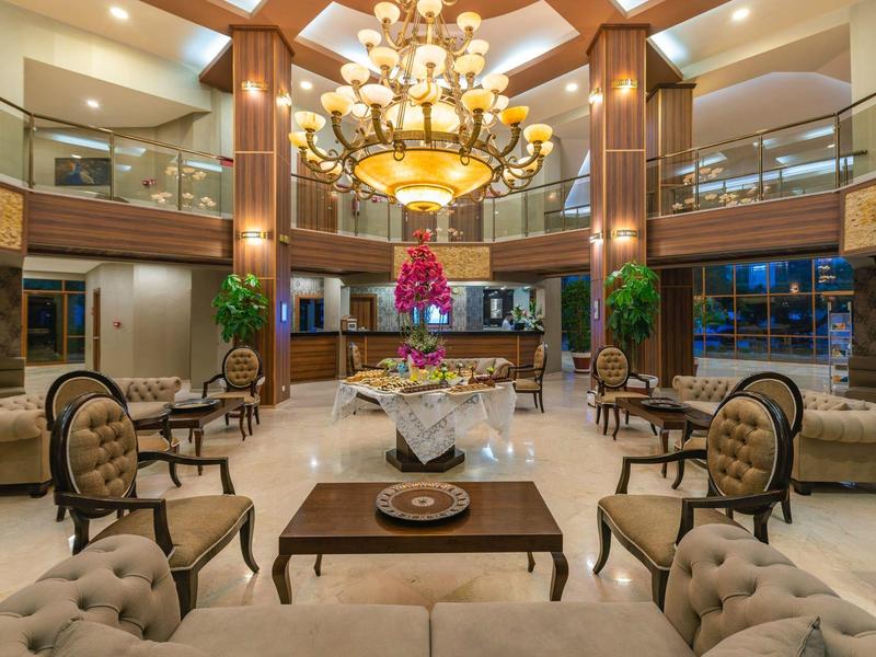 Elegante hall dell'hotel con lampadario, poltrone e grande composizione floreale al centro.