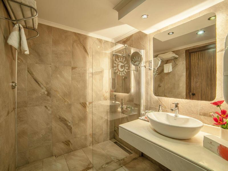 Bagno moderno con doccia in vetro, lavabo e fiore decorativo sul banco.