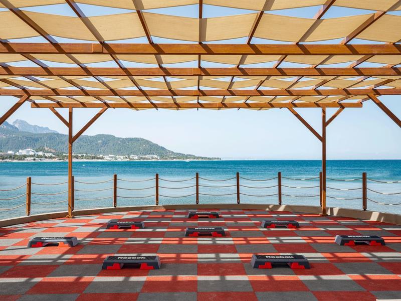 Terraza cubierta con suelo colorido con vista al mar y montañas al fondo.