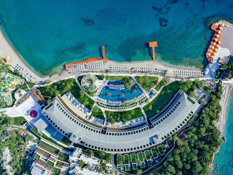 Vista aérea de un gran resort con edificios semicirculares y muelles sobre el mar turquesa