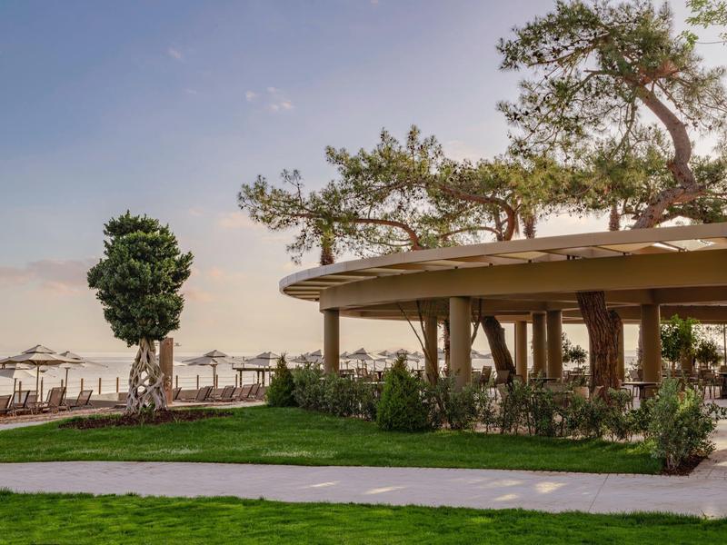 Pabellón moderno en el jardín del hotel con vista a la playa y al mar al fondo.