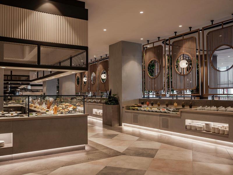 Área de buffet elegante con vitrinas de vidrio modernas y luz cálida en un restaurante de hotel.