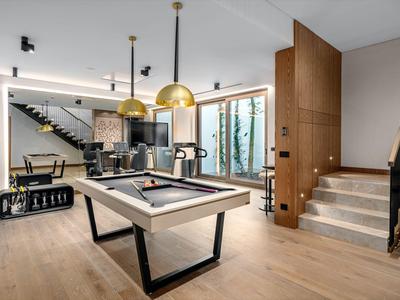 Nowoczesny pokój gier z bilardem, schodami, dużym oknem i wysokiej jakości jasnym drewnianym umeblowaniem.