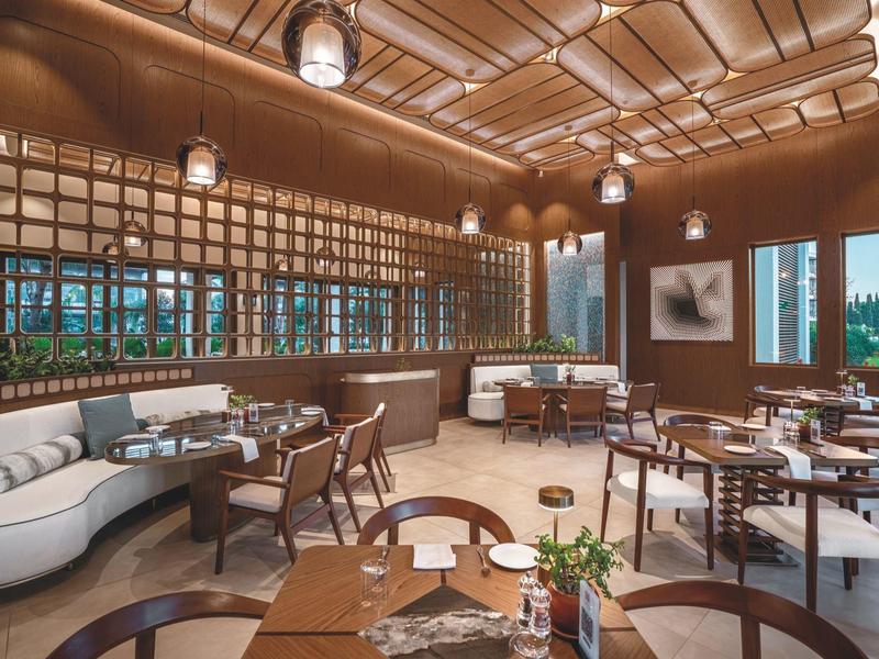 Ristorante elegante con mobili moderni, grandi finestre e caldi accenti in legno.