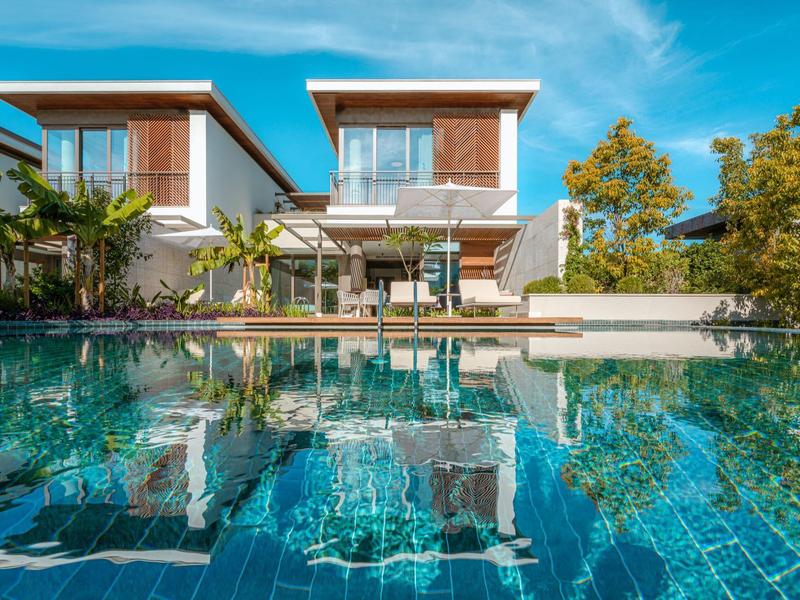 Casa vacanze moderna con grande piscina e area esterna sotto il cielo azzurro.