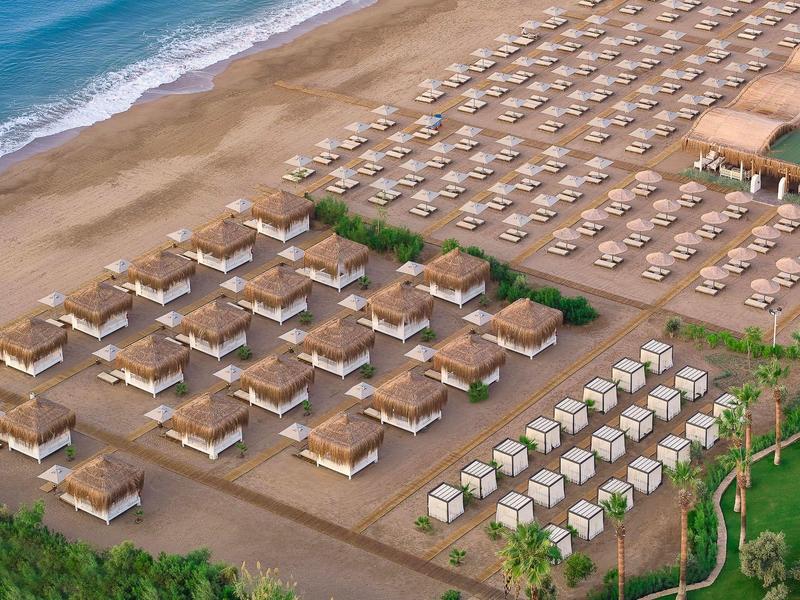 Spiaggia con lettini e cabine ordinatamente disposti lungo la costa.