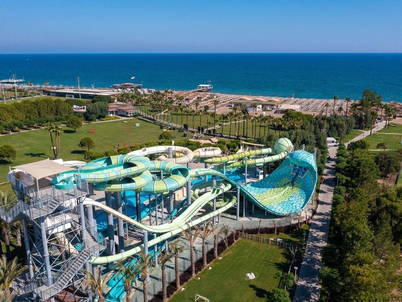 Grande parco acquatico con scivoli vicino a una spiaggia e al mare sullo sfondo.