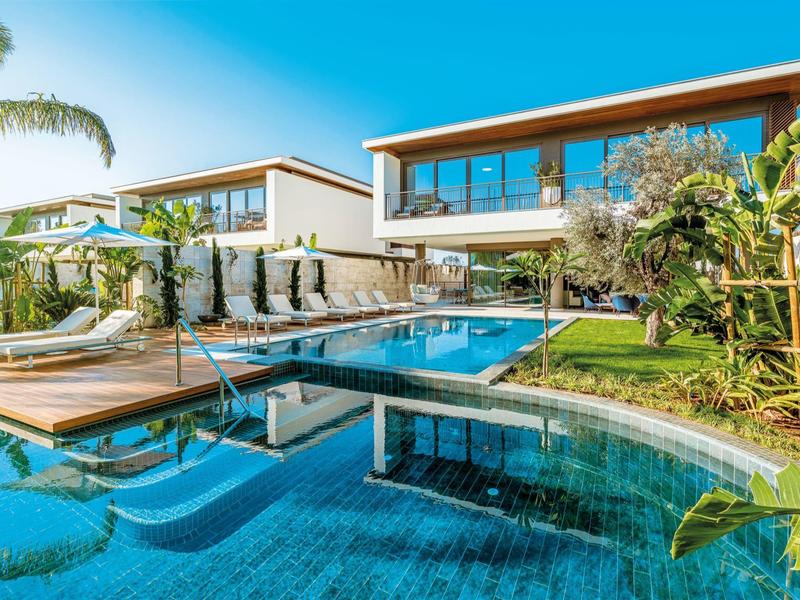 Area piscina moderna con pareti in vetro e lettini in una casa vacanze di lusso.