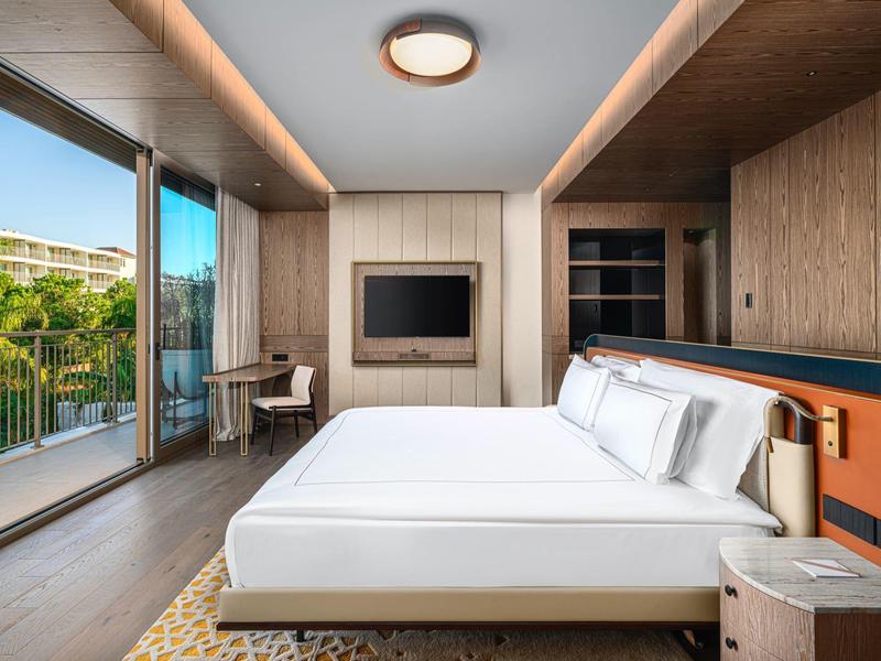 Camera d'hotel moderna con letto matrimoniale, balcone e vista sul verde.